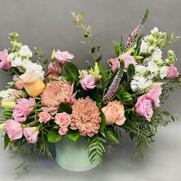 Pink and peach floral arrangement in a pale green vase