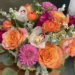 Bouquet of orange and pink roses with white orchids and purple blooms