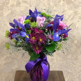 Bouquet of purple irises and pink daisies in a purple vase