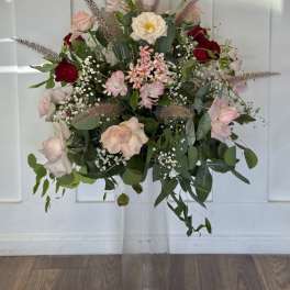 Mixed pink and red roses in a clear pedestal vase