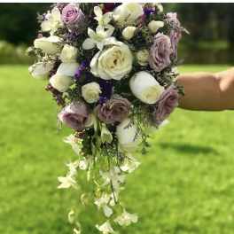 Handheld bouquet of white and lavender roses with trailing white orchids
