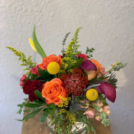Mixed bouquet in a clear glass vase with orange and purple blooms