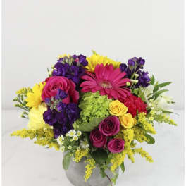Colorful bouquet of roses, gerbera daisies, and mixed blooms in a gray vase
