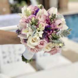 Handheld bouquet of pink and white flowers with purple accents