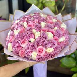 Large bouquet of pink, lavender, and white roses wrapped in pastel paper