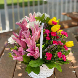 Basket of pink lilies, yellow tulips, and mixed blooms