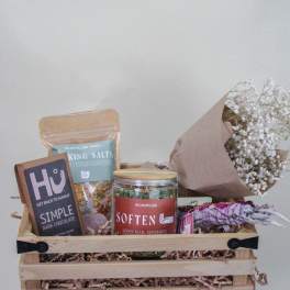 Gift basket with chocolates, bath salts, tea, and a small bouquet of white baby's breath