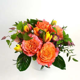 Orange and pink roses with yellow tulips in a white vase