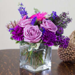 Purple and pink flower arrangement in a clear glass vase
