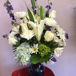 White lilies, roses, and daisies in a dark vase