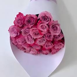 Bouquet of pink roses wrapped in white paper with a lavender ribbon
