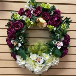 Floral wreath with purple roses and white flowers on a wooden wall
