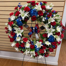 Large red, white, and blue floral wreath on a stand with ribbon
