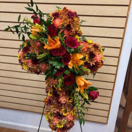 Cross-shaped floral standing spray with red, orange, and yellow blooms