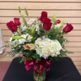 Red roses and white hydrangea in a glass vase with a ribbon