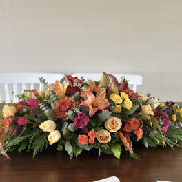 Low floral centerpiece with roses, lilies, and chrysanthemums in autumn colors