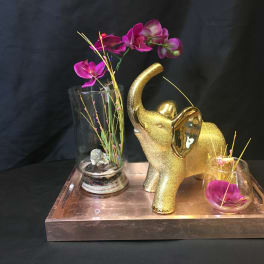 Gold elephant figurine with purple orchids in glass vases on a tray