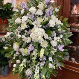 Large white and lavender funeral spray on an easel