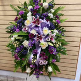 Standing floral spray with purple and white flowers on a metal easel