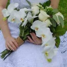 Bride holding a white orchid bouquet with greenery