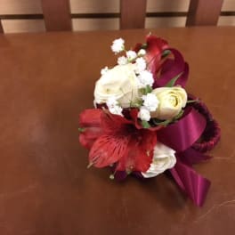 Small bouquet of white and red flowers with a purple ribbon