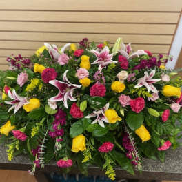 Large mixed floral arrangement with yellow roses, pink carnations, and lilies