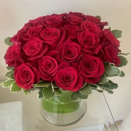 Compact dome of red roses in a clear glass vase
