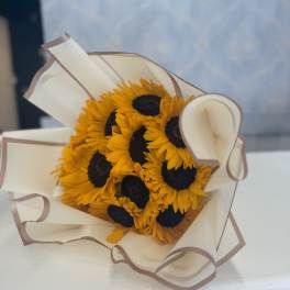 Bouquet of sunflowers wrapped in cream paper with brown trim