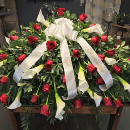 Large funeral spray of red roses and white calla lilies with white ribbons