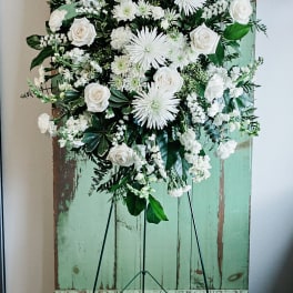 White floral standing spray on a black easel