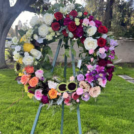 Large floral wreath on an easel with roses in red, white, pink, and purple