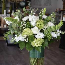 White and green floral arrangement in a glass vase