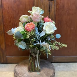 Bouquet of pale roses and coral blooms in a glass vase