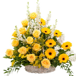 Yellow roses and gerbera daisies in a wicker basket