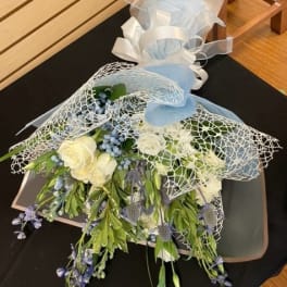 Bouquet of white and blue flowers wrapped in mesh and ribbon