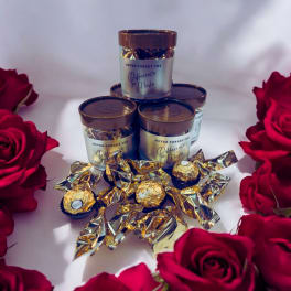 Red roses surround stacked gift jars and wrapped chocolates.