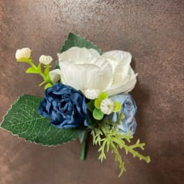 Small blue and white floral boutonniere with green leaves