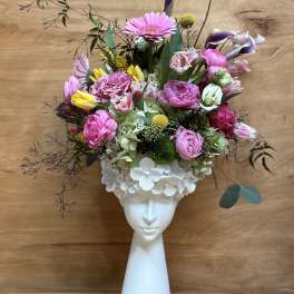 Pink and white floral arrangement in a white face vase