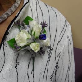 White and purple boutonniere pinned to a sequined jacket
