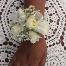 White rose wrist corsage with ribbon on a person's wrist