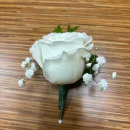White rose boutonniere with baby's breath on a wooden surface
