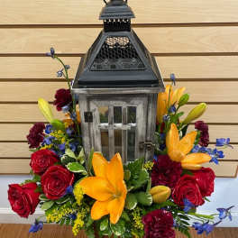 Lantern centerpiece surrounded by red roses and yellow lilies