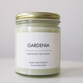 A gardenia-scented candle in a glass jar with a gold lid