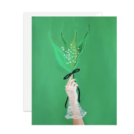 Hand holding a small lily-of-the-valley bouquet on a green card