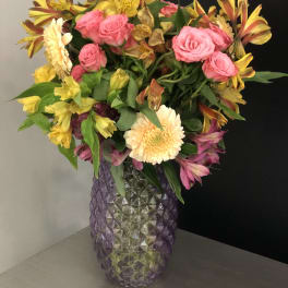 Mixed bouquet of pink roses and yellow alstroemeria in a purple glass vase