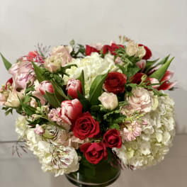 Bouquet of red roses, pink tulips, and white hydrangeas in a glass vase