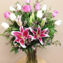 Pink and white lilies with roses in a glass vase