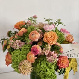 Bouquet of orange and pink flowers in a green glass vase