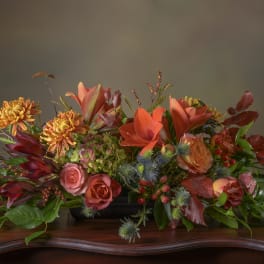 Autumn floral arrangement with orange lilies, roses, and chrysanthemums