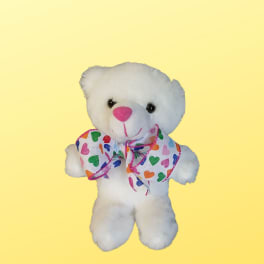 White teddy bear with a colorful heart-pattern bow on a yellow background